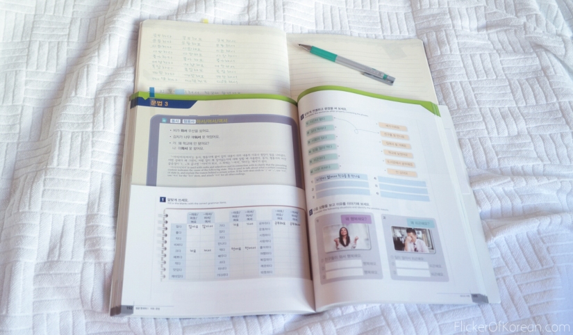 studying from korean textbook on bed with notebook